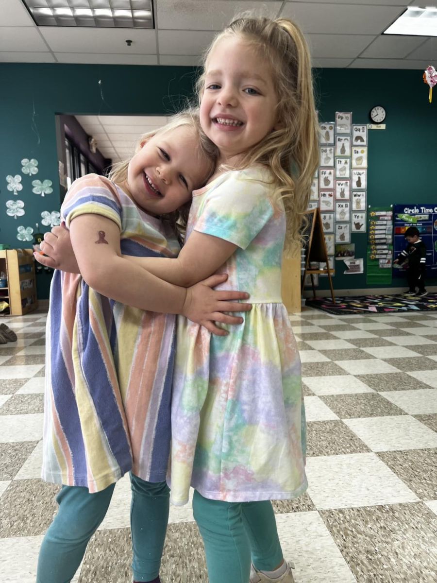 Two school-age childcare girls hugging at The Club House daycare center.