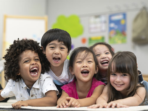 Five smiling and laughing kids at The Club House childcare center.